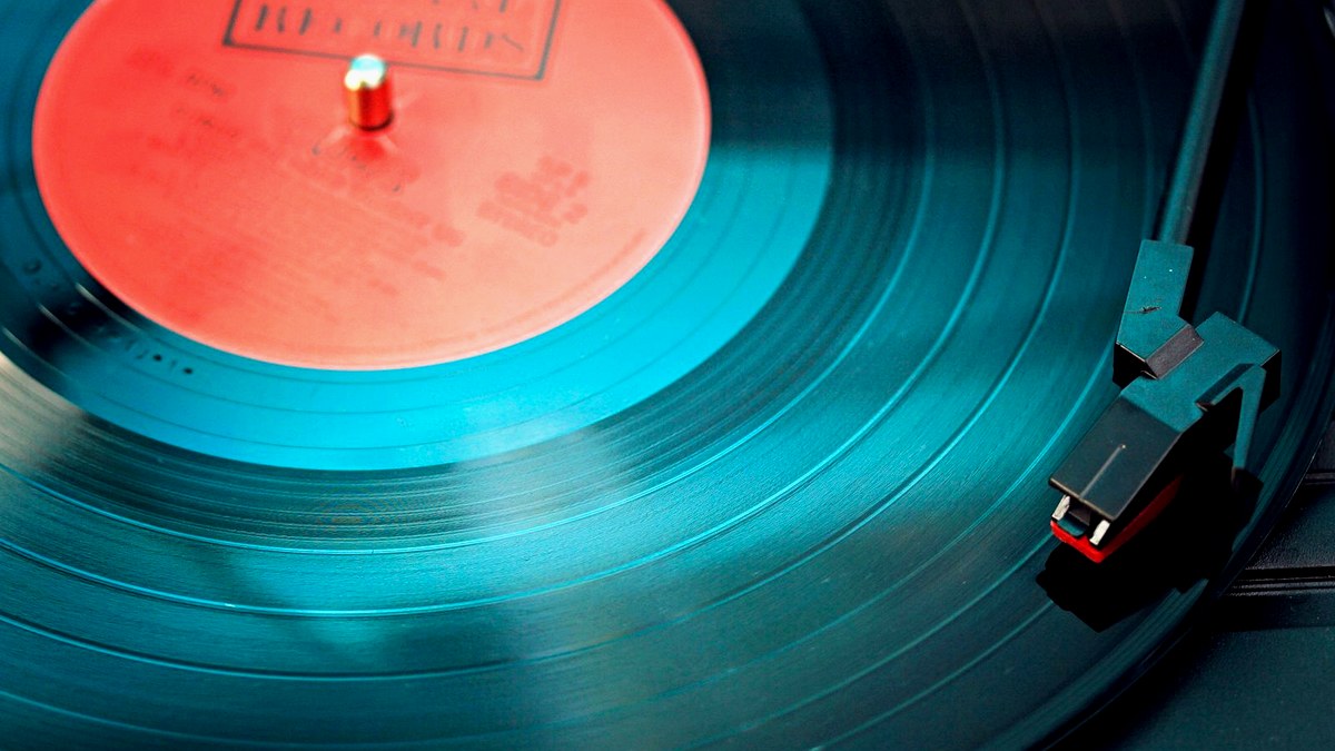 Editorial cover: teal vinyl on turntable with red label under cool cyan sidelight for Victoria Monet Frequency of Love.