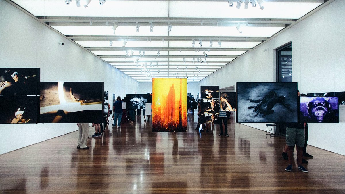Editorial cover: modern museum gallery with suspended prints and skylight for De Kooning Rijksmuseum 2026.