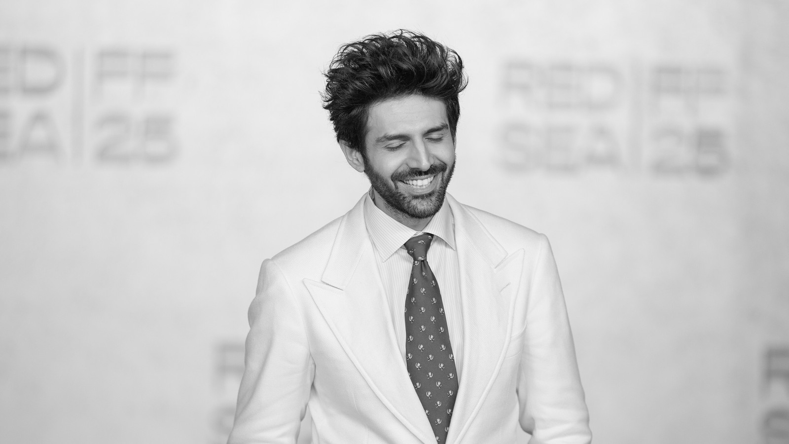 Actor Kartik Aaryan in a white suit at the Red Sea International Film Festival