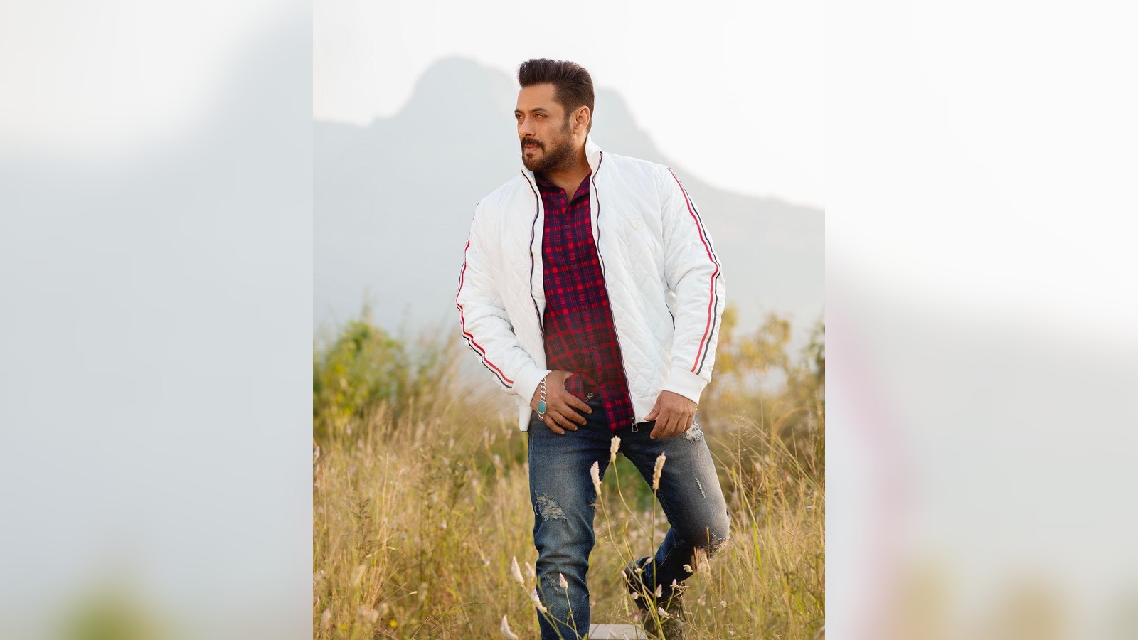 Actor Salman Khan in a white jacket standing in a field