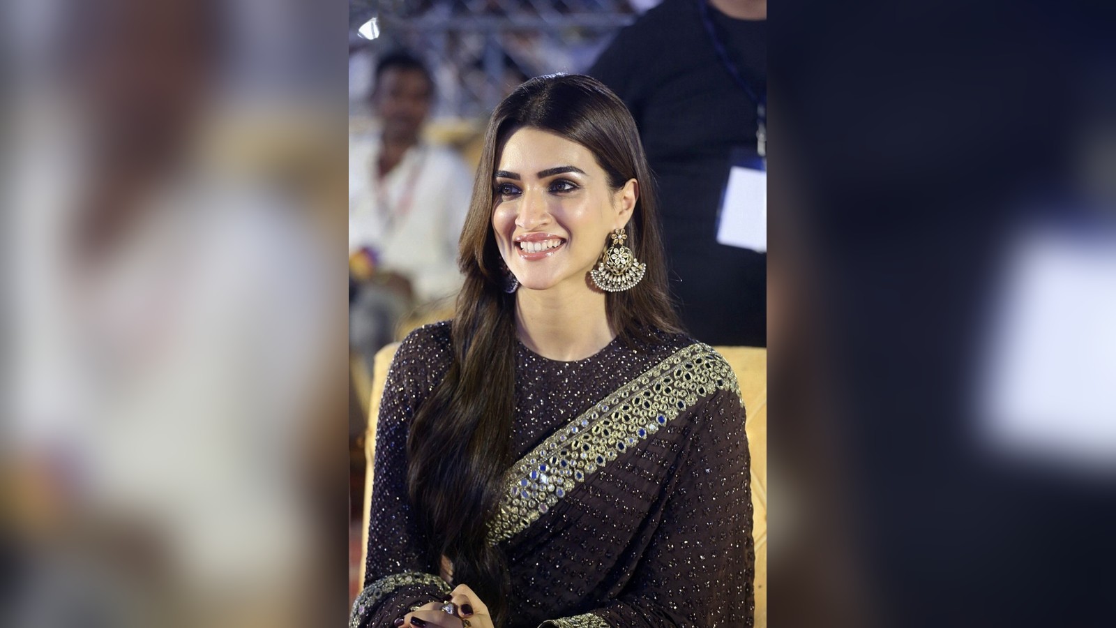 Actor Kriti Sanon smiling in a dark embroidered saree