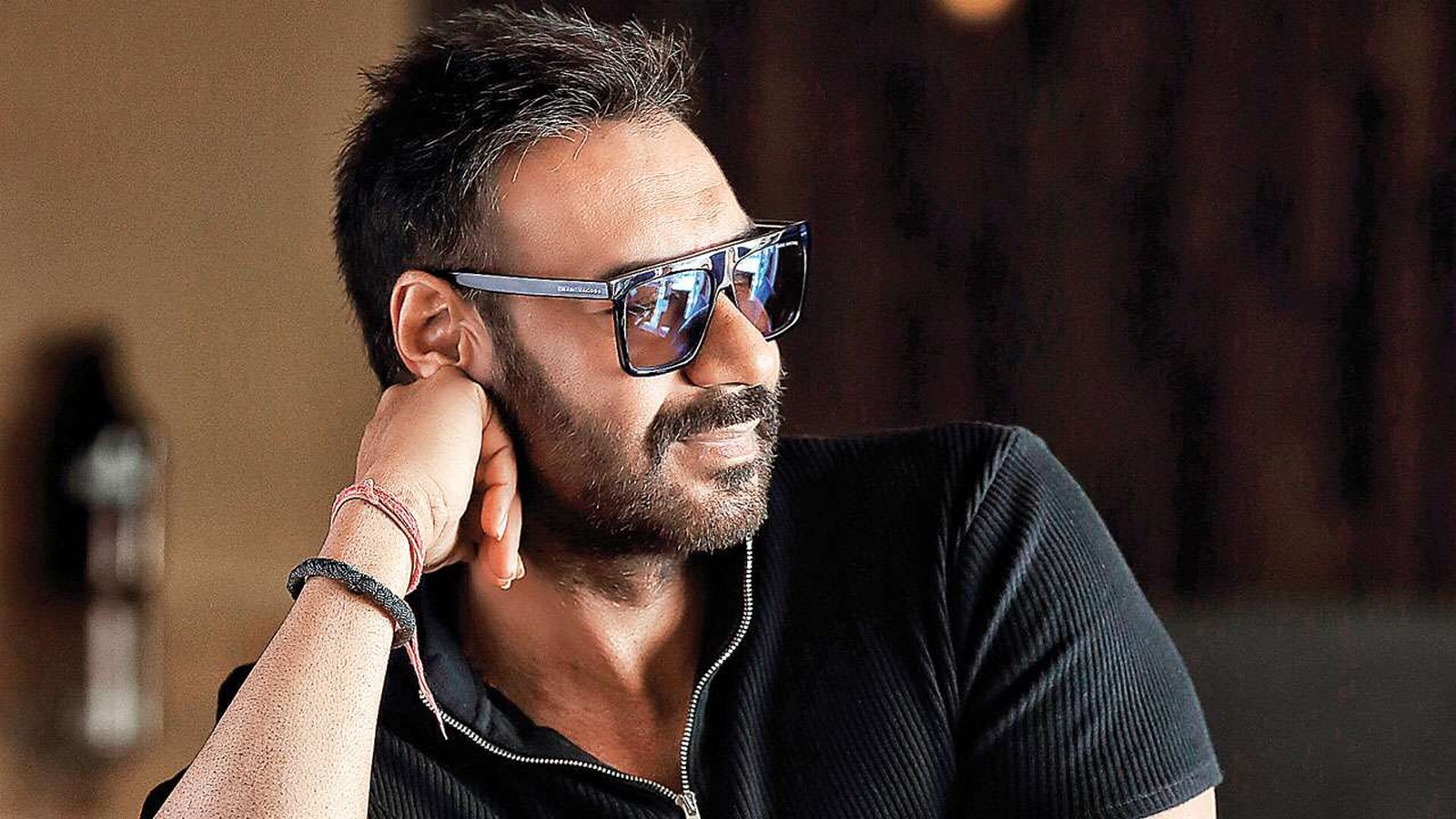 Actor Ajay Devgn in sunglasses with his hand at his face