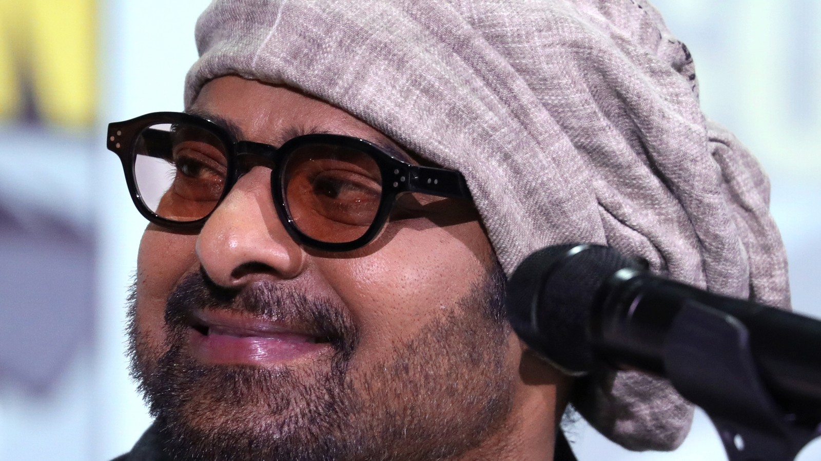 Actor Prabhas wearing a cap and glasses at a convention panel