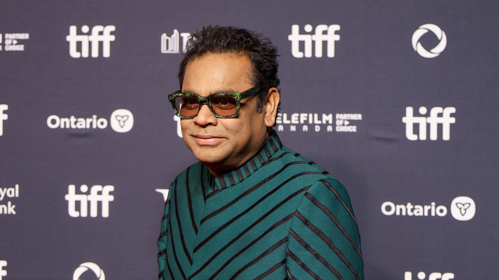 Composer A. R. Rahman in tinted glasses and a green striped sweater at TIFF 2025