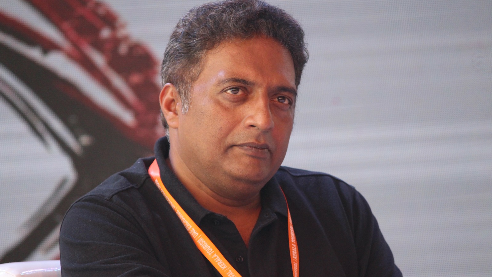 Actor Prakash Raj wearing a lanyard and speaking at an event in Calicut