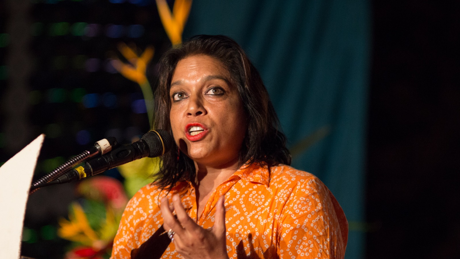 Director Mira Nair speaking into a microphone in an orange top at the Zanzibar film festival