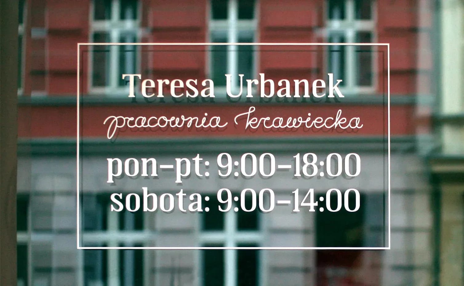 Napis na drzwiach Pracowni Krawieckiej Teresy Urbanek. Sign on the front door of Teresa Urbanek Tailor’s Workshop with hours of opening.