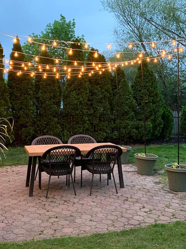 string lights above wooden outdoor dining table