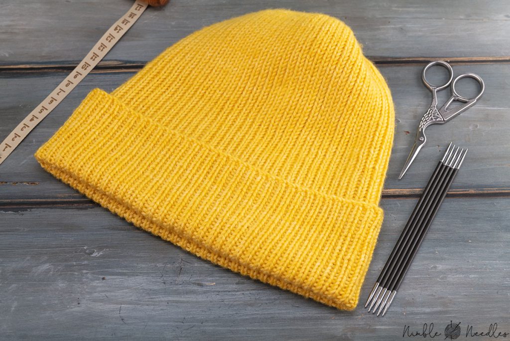 knit beanie made from old sweater on wooden surface
