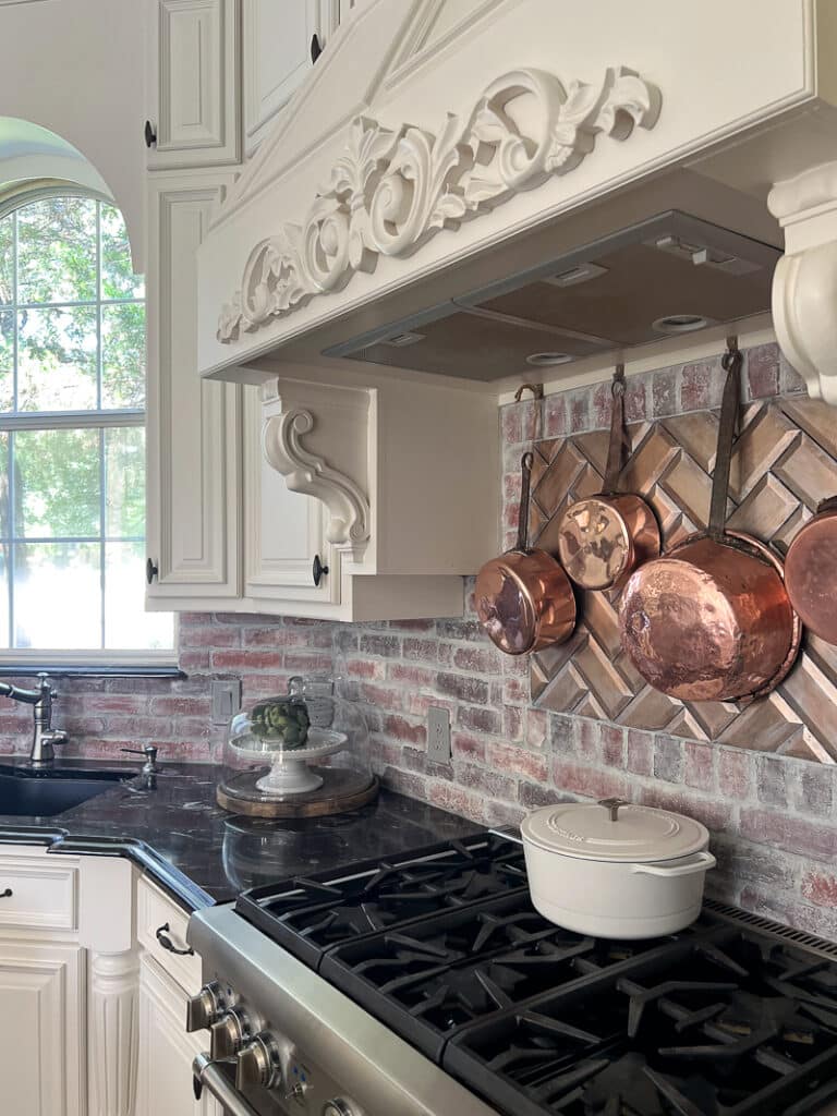 copper cookware hanging above kitchen stove with fall accents