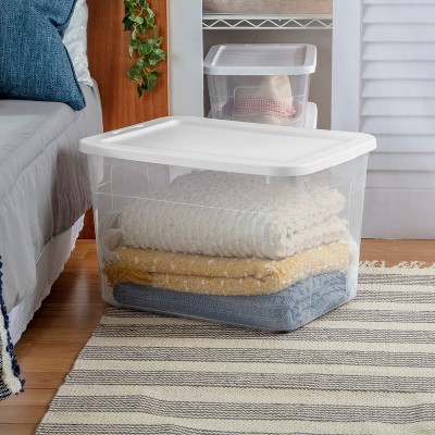 stacked throw pillows in clear storage bin