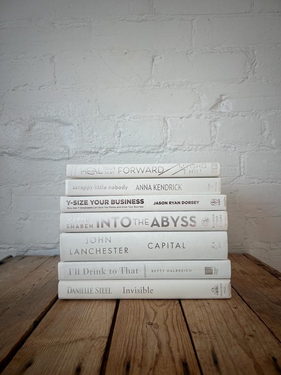 white books stacked on wooden shelf