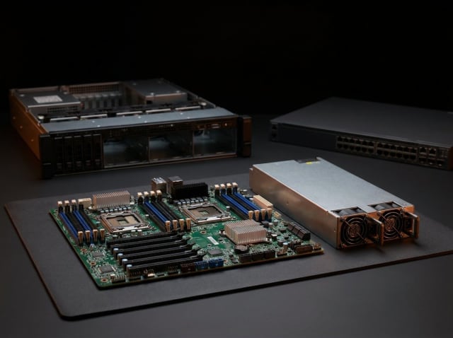 Server və şəbəkə avadanlığının təmiri — arxada server şassisi və switch, önündə anakart və qida bloku