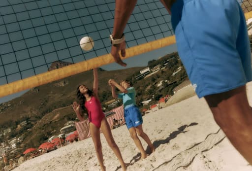 Kinder spielen Volleyball am Strand.