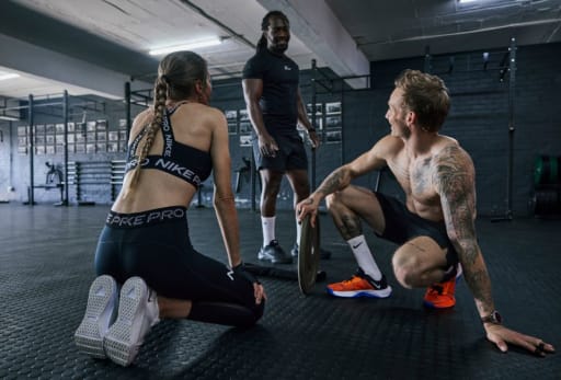 Drei Personen im Fitnessstudio unterhalten sich.