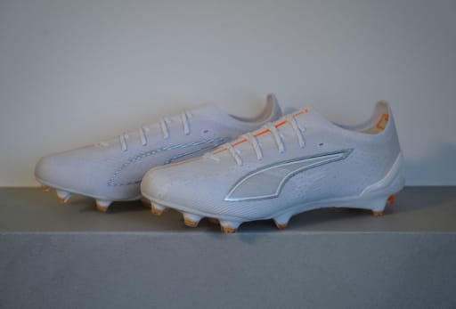 Ein Paar weiße Puma White Fussballschuhe mit orangem Akzent.