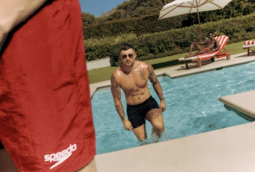 Ein Mann laeuft aus einem Pool heraus.