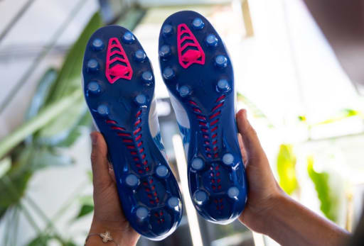 Ein Mann haelt ein Paar Mizuno Urban Electric Fussballschuhe in der Hand.