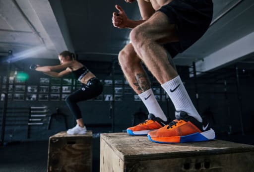 Zwei Personen springen im Fitnessstudio auf Boxen.