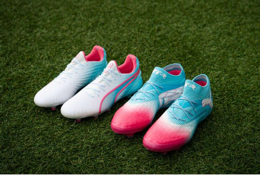 Zwei Paar Puma Re-Charge Fussballschuhe stehen auf dem Rasenplatz nebeneinander.