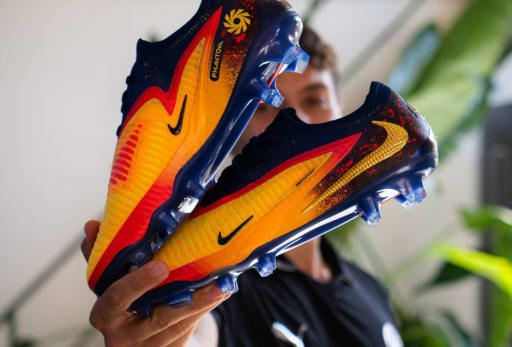 Nike Haaland Phantom 6 Fussballschuhe werden in die Kamera gehalten.