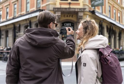 Mann und Frau laufen durch die Stadt und machen Fotos.