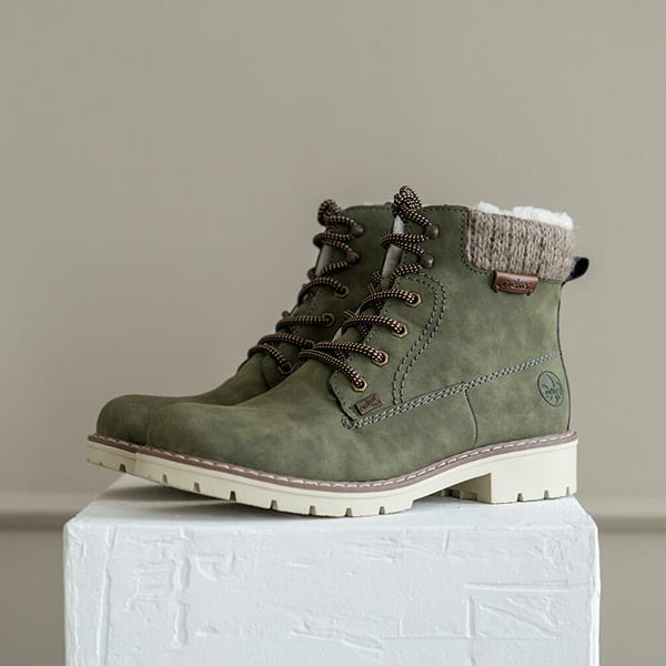 Gruene Schnürboots für Damen stehen auf weißem Hocker.