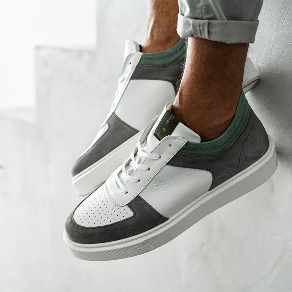 Mann traegt sportliche Sneaker in weiß/grau am Fuss.