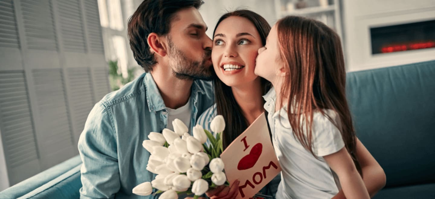 Dziecko i mąż całuje kobietę w policzek na Dzień Matki