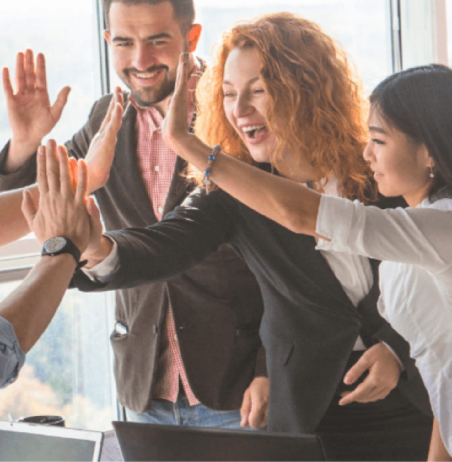 Grupa ludzi ,która przybija sobie piątki w pracy