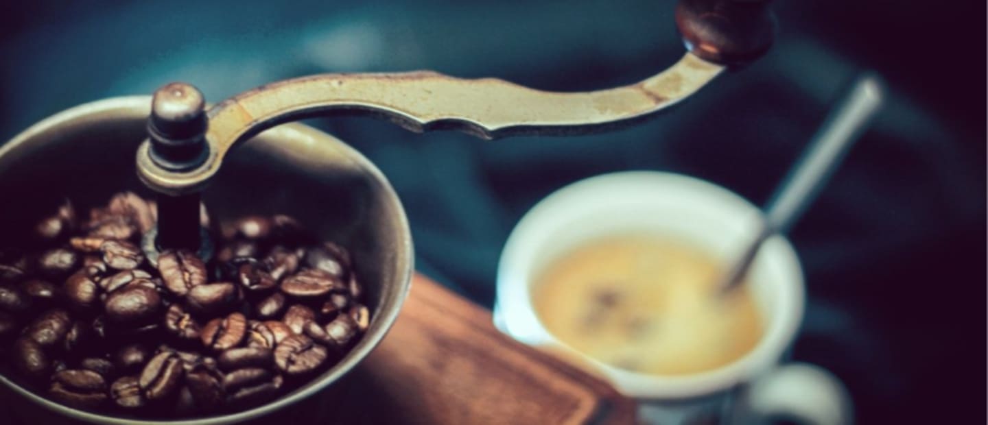 kawa w ziarnach w młynku do kawy przy filiżance czarnej świeżoparzonej kawy