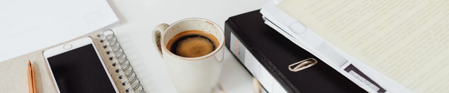 Segregatory, teczki i kawa na biurku