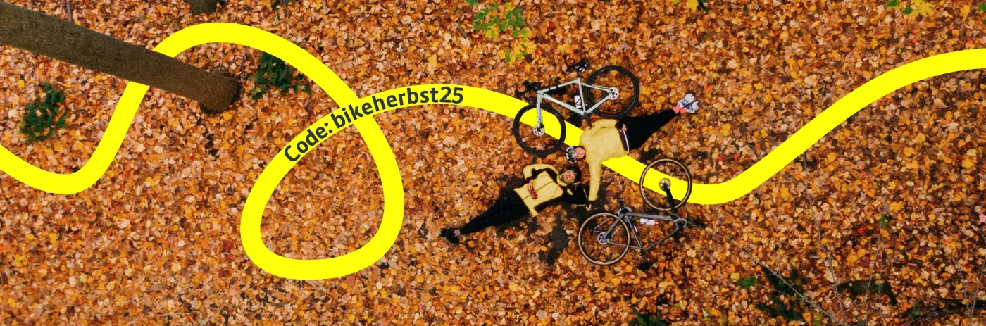 Ein Paar liegt mit ihren Gravelbikes zusammen im Herbstlaub.