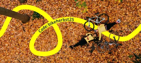 Ein Paar liegt mit ihren Gravelbikes zusammen im Herbstlaub.