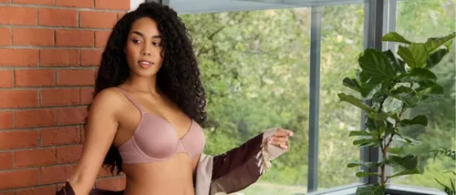 female wearing a robe and vanity fair effortless bra by a window