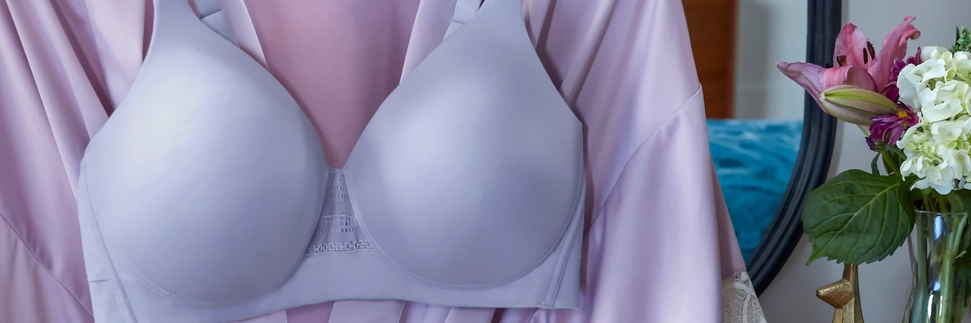Three women wearing bras in pink, blue, and gray stand side by side outdoors.