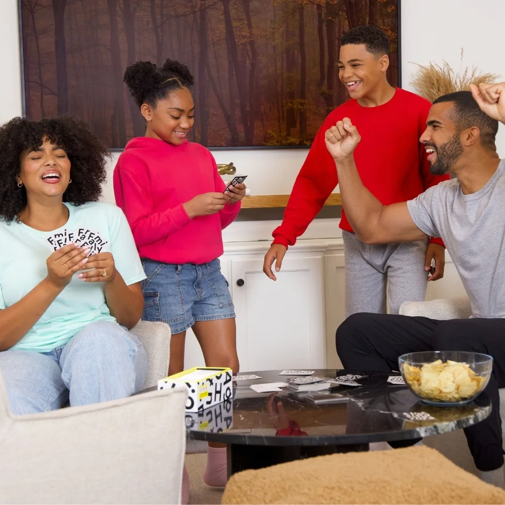 Family playing cards in living room. Everyone is wearing Fruit of the Loom fleece and apparel items.