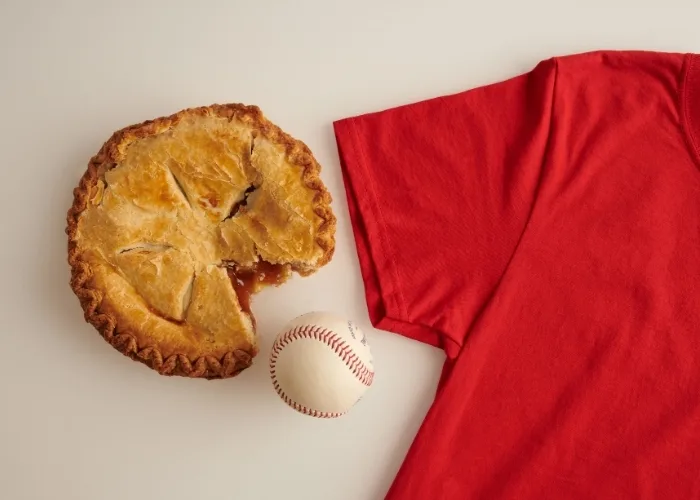 layflat of a RA tshirt positioned beside a baseball and pie