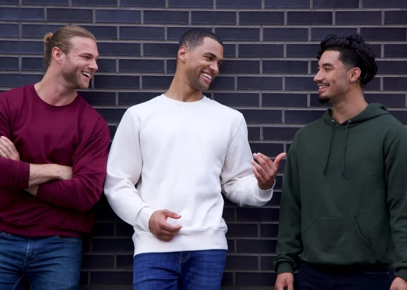 men in sweatshirts talking in front of a brick wall