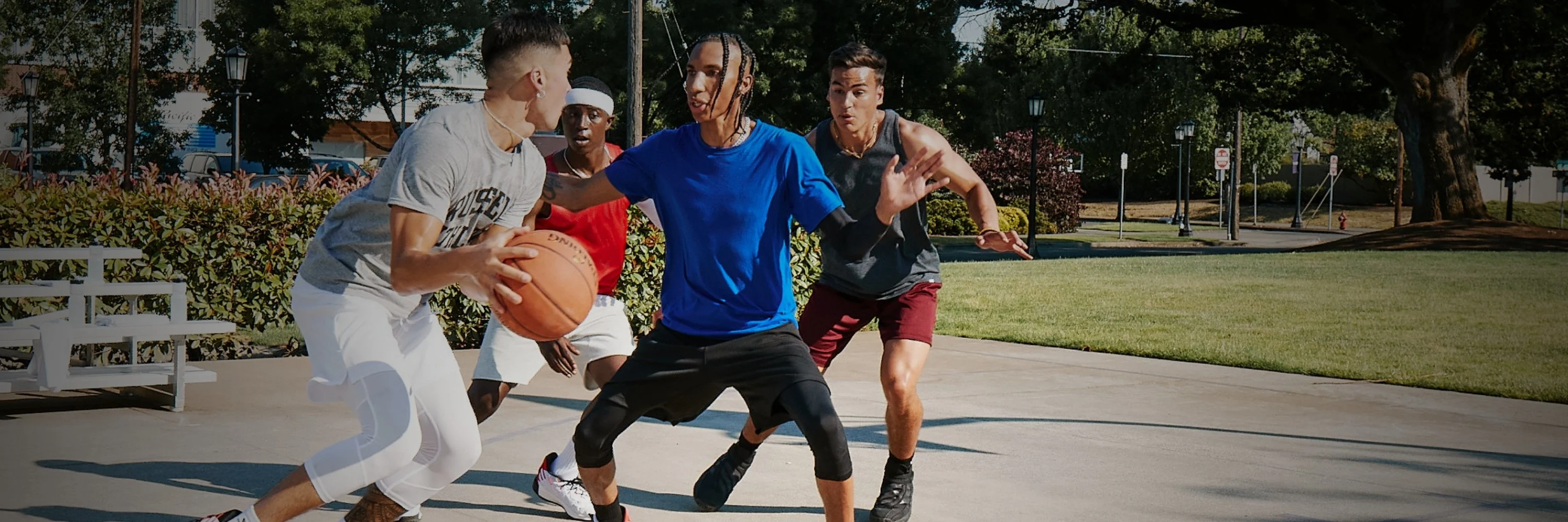 Group of players on outdoor basketball court using featuring a TF outdoor basketball and active gameplay under clear sky.