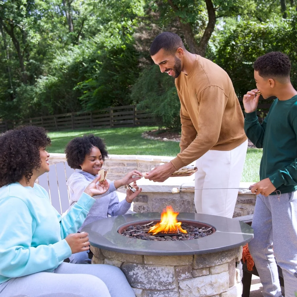 Family gathered outside around a firepit making smores. They are all wearing fleece sweatshirts.