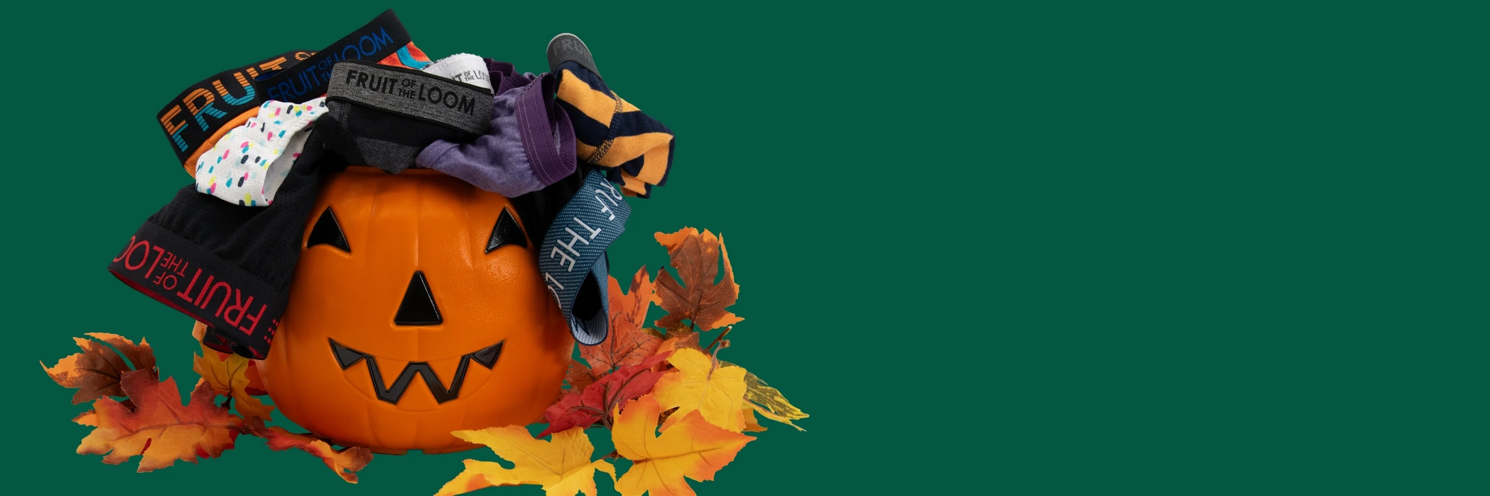 A Halloween pumpkin bucket with leaves around it and underwear coming out of it.