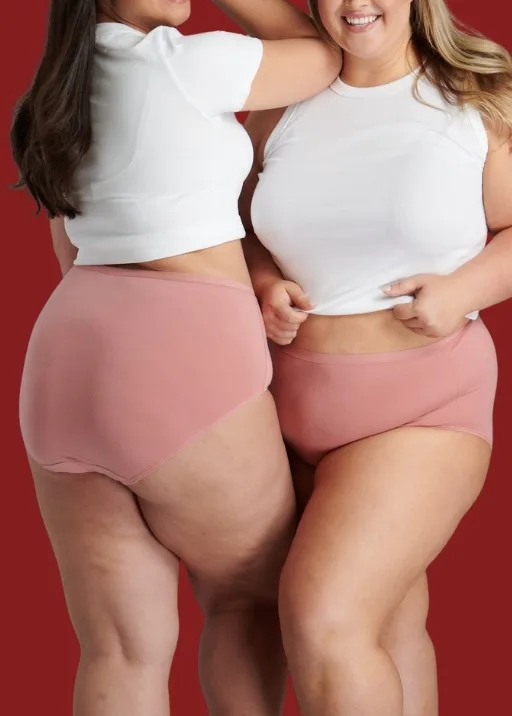 Two women wearing Fit For Me pink briefs with white t-shirts on.