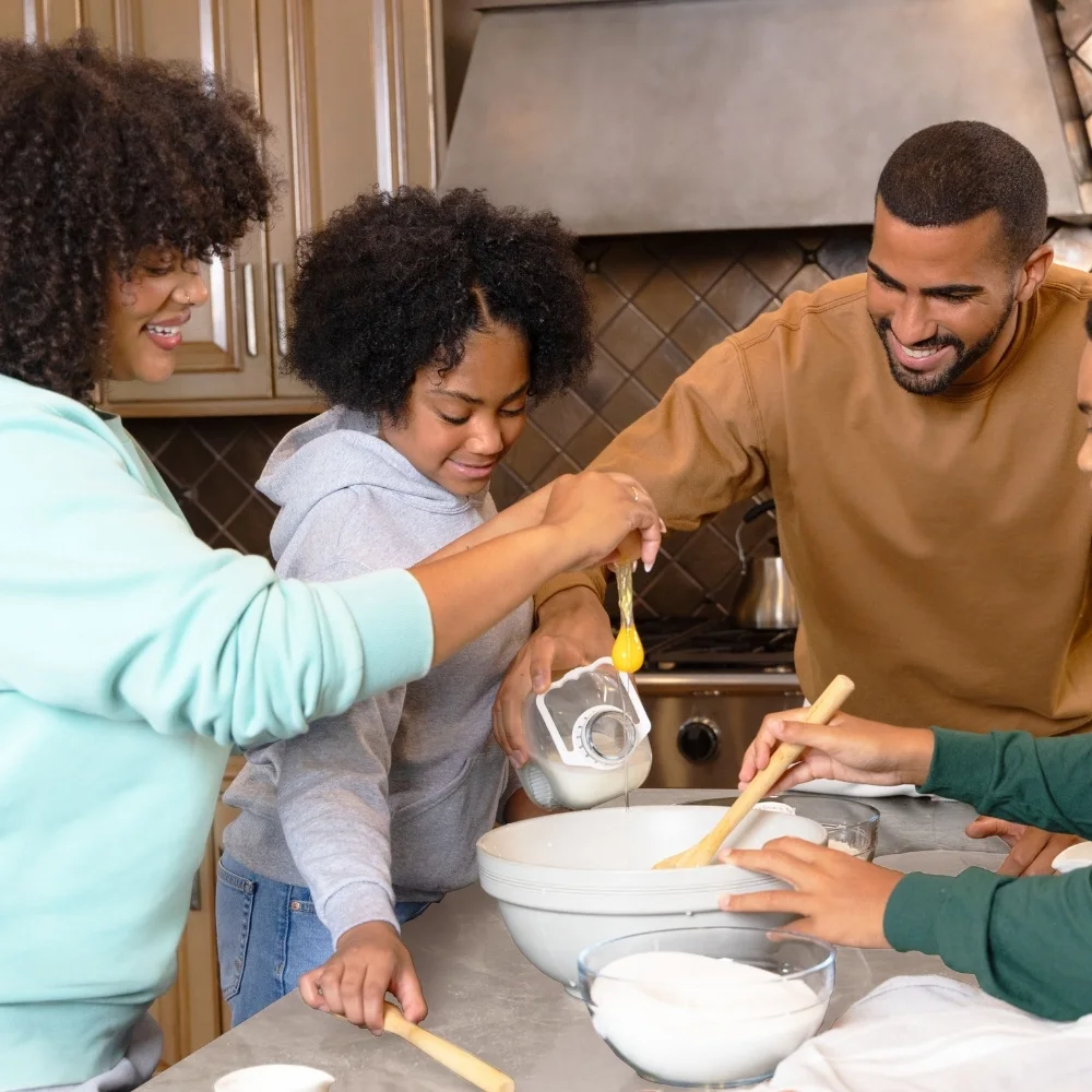 Family cooking together in the kitchen. Everyone is wearing fleece sweats.