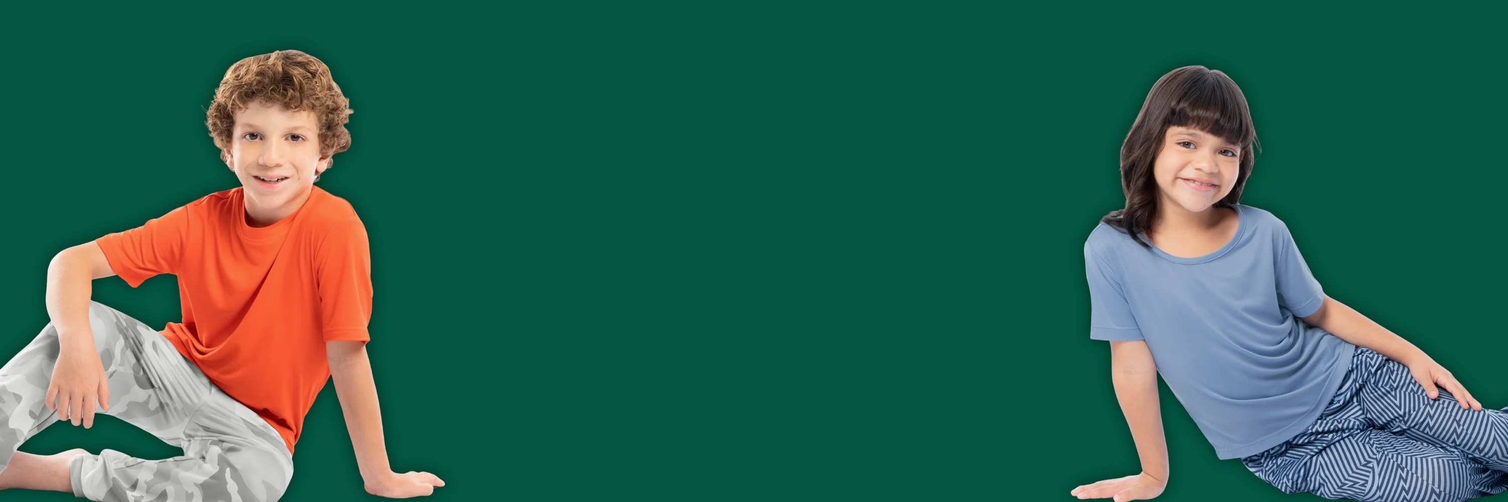 A boy and a girl both wearing pajamas with a dark green background.