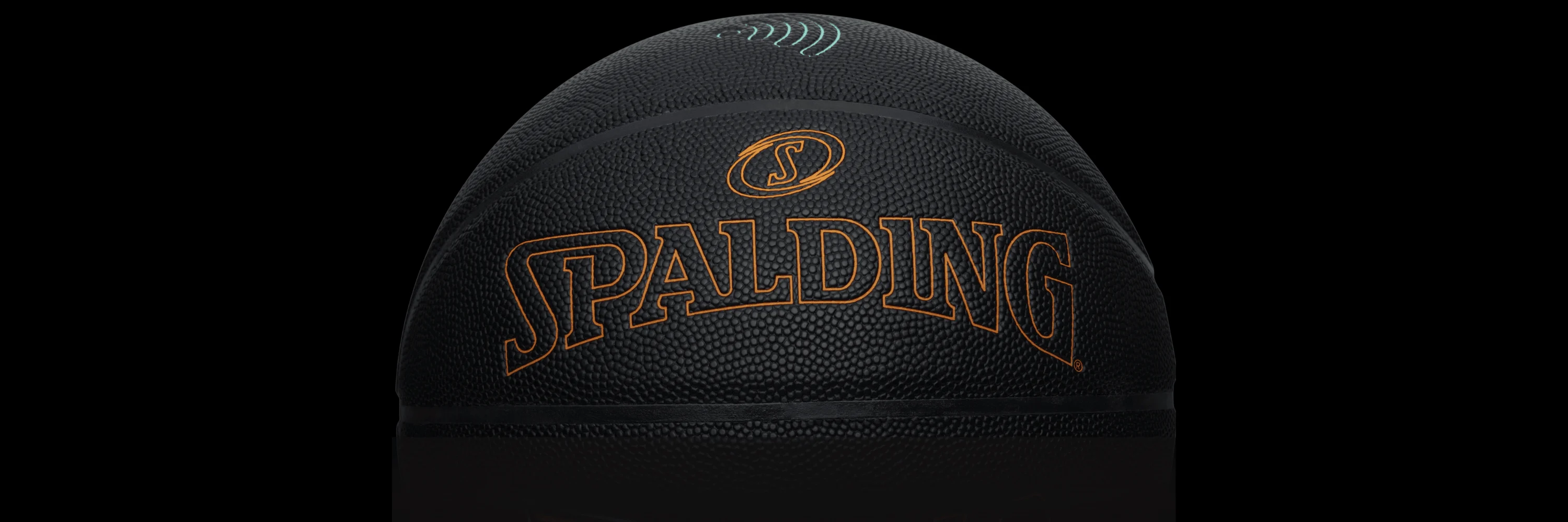 Close-up of a black Spalding TF DNA SmartBasketball with an orange Spalding logo and a teal signal icon, set against a black background to emphasize the ball’s texture and design.