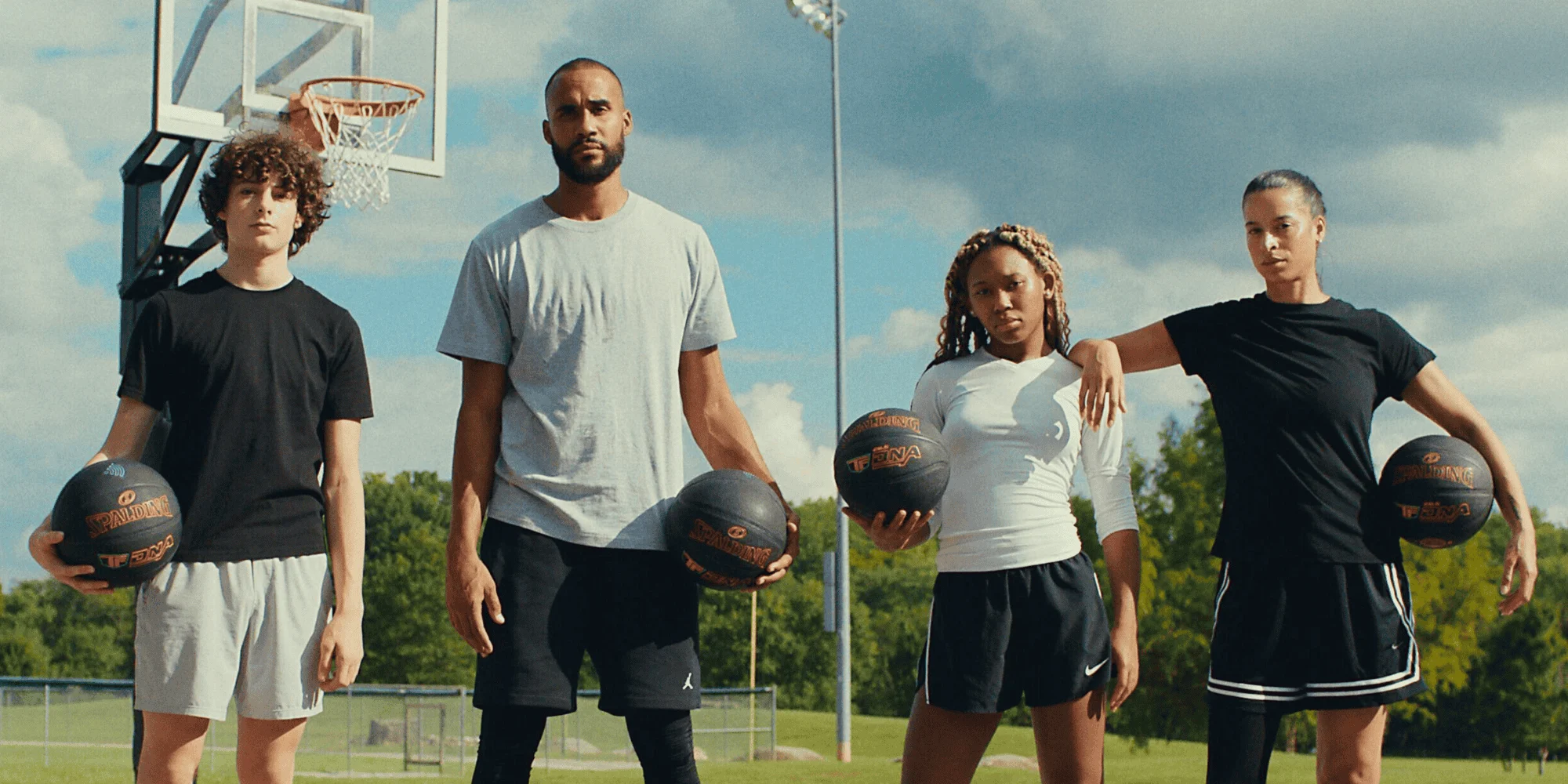 4 basketball players holding TF DNA Smart basketballs in each hand on an outdoor court.