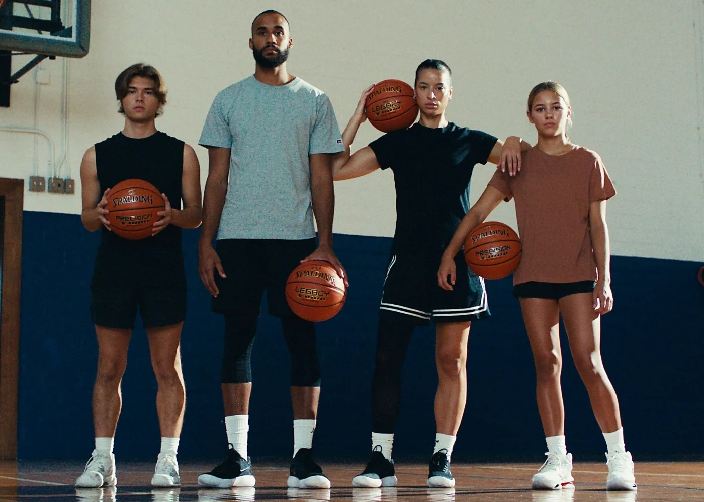 basketball players holding legacy and precision basketballs standing in a gym