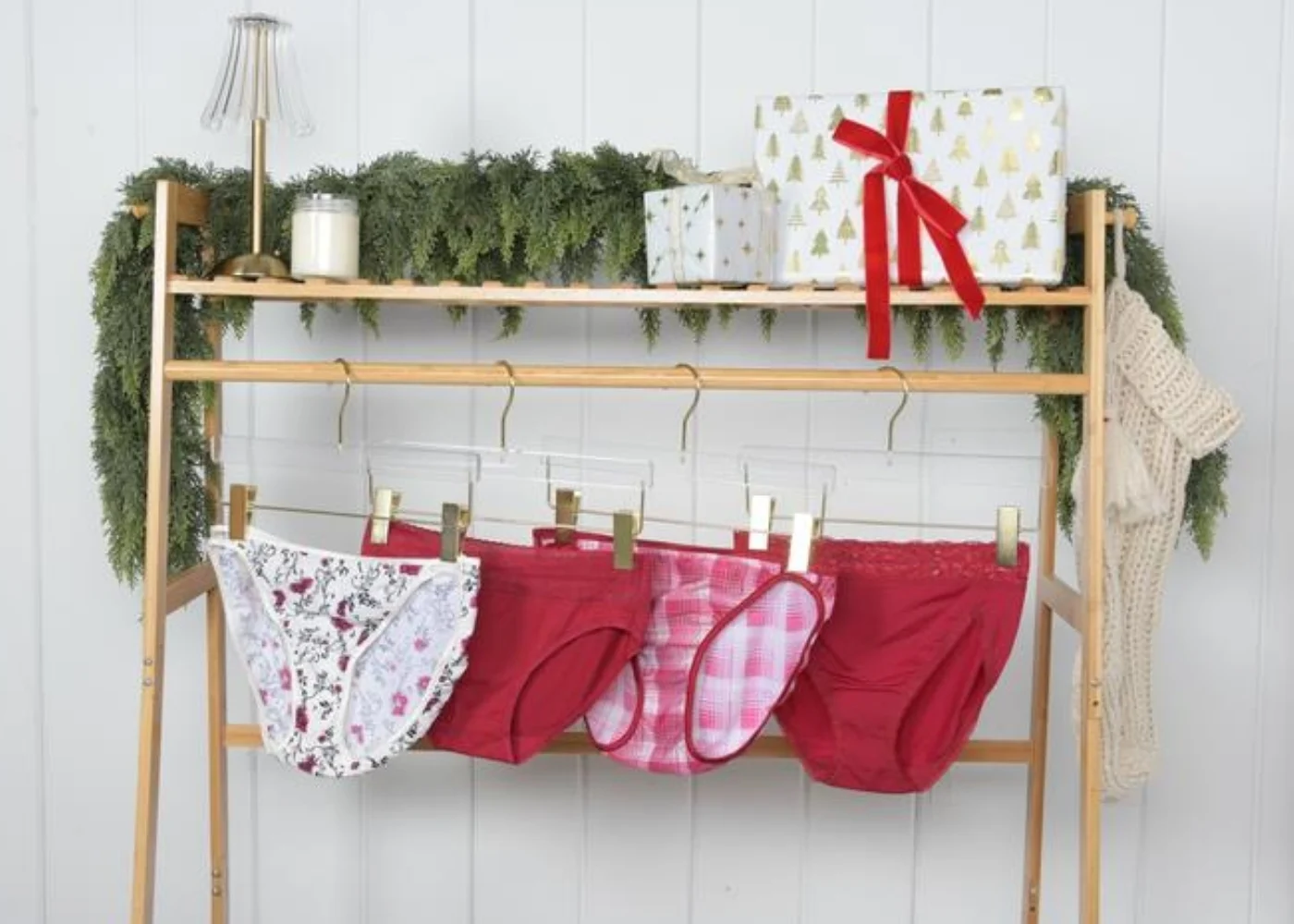 A chic flat lay featuring a black bra, matching panties, and black shapewear shorts styled with a taupe ribbed sweater. Accessories include gold jewelry and black heeled boots, creating a sophisticated, modern vibe.