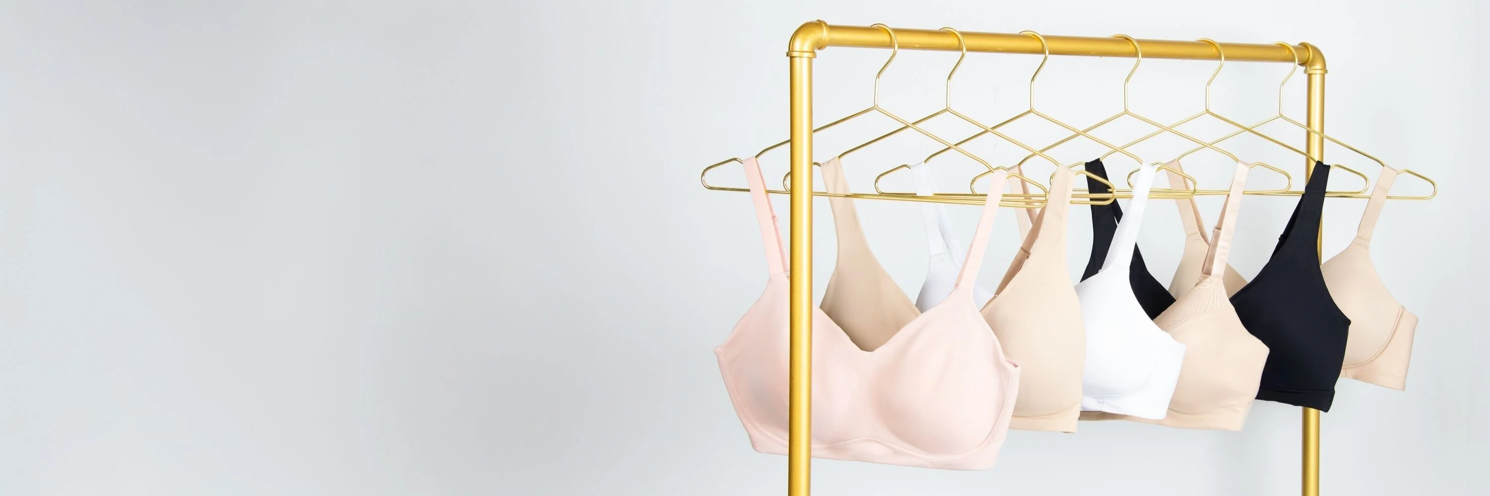 variety of different style vanity fair lingerie bras hanging on a gold rack